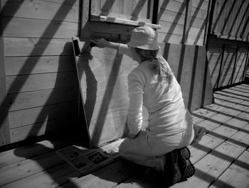 Rear view of women painting wooden plank