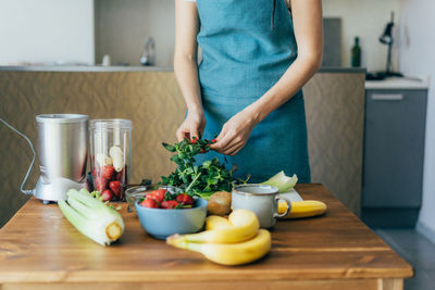 Midsection of woman cleaning mint leaf at home