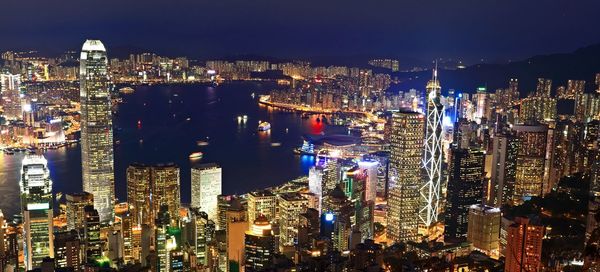 Panoramic view of illuminated cityscape by river against sky