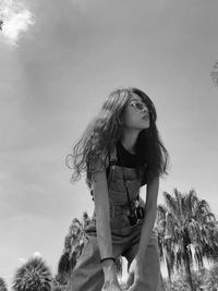 Low angle view of young woman standing against sky