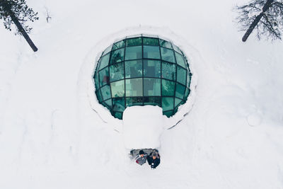 Aerial view of male friends standing at hotel amidst snow covered field