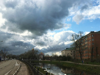 Road by buildings in city against sky