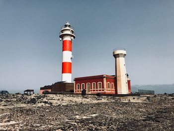 Low angle view of lighthouse by building against sky