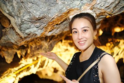 Portrait of young woman standing against rock