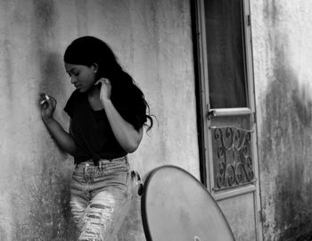 Young woman standing by wall