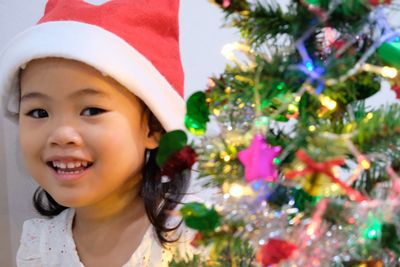 Portrait of cute girl by christmas tree at home