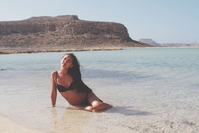 Portrait of woman in bikini standing at beach