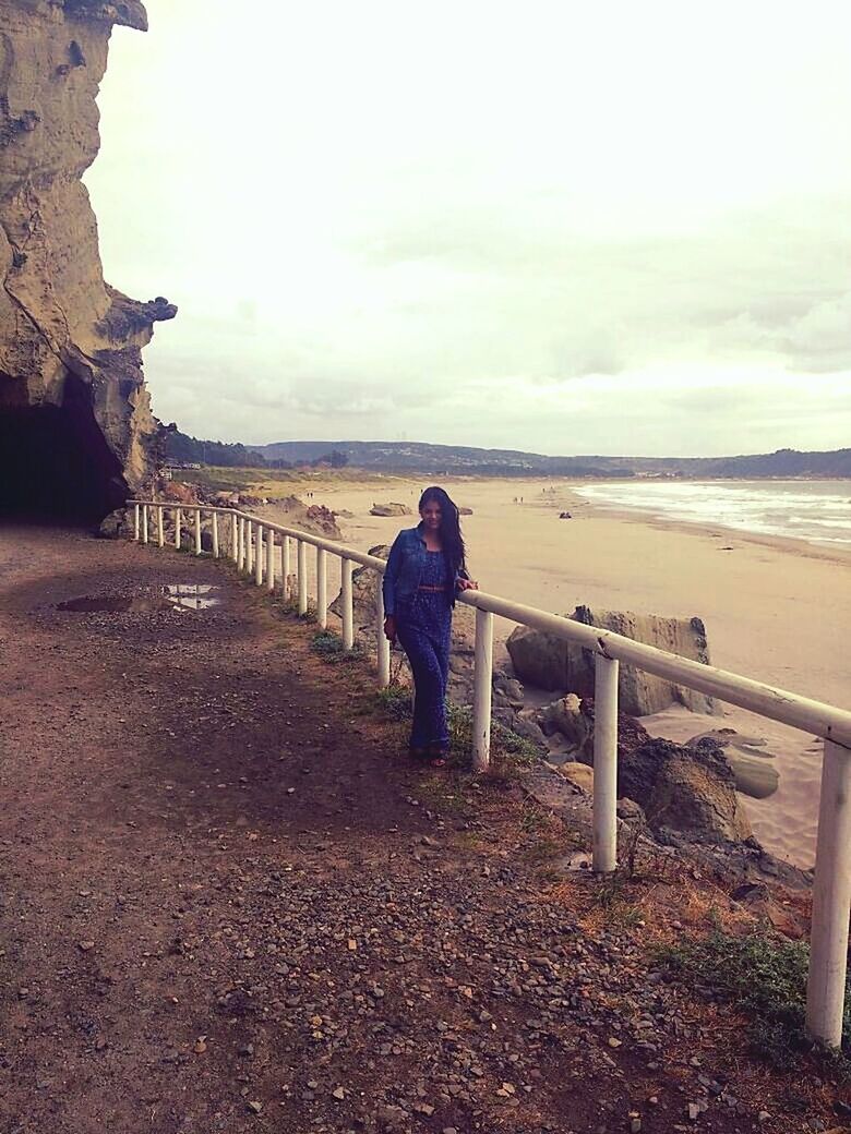 FULL LENGTH OF WOMAN STANDING ON BEACH AGAINST SKY