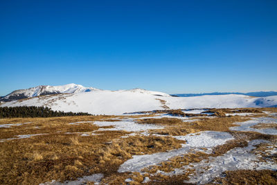 Scenic view of snowcapped mountains against clear blue sky