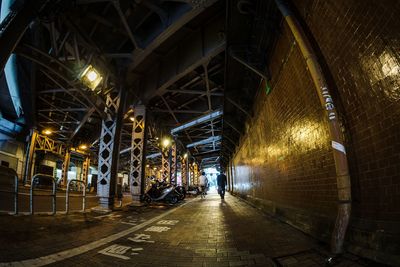 People walking on illuminated footpath amidst buildings in city at night