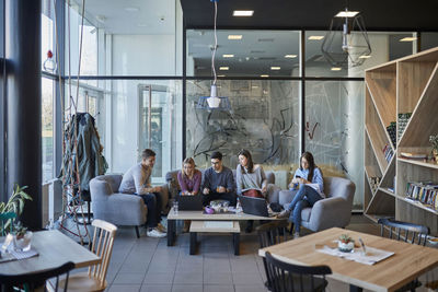 Group of friends sitting together in a cafe with laptop