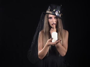 Portrait of young woman using mobile phone against black background