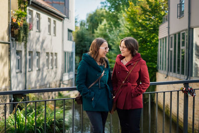 Sisters standing by railing in city