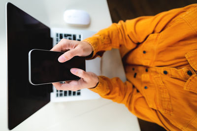 Cropped top view of businesswoman's hands with smartphone at white office table. mobile phone with