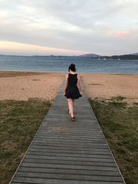 Rear view of woman on beach against sky