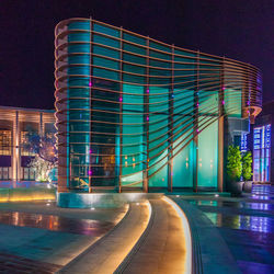 Light trails on building against sky at night