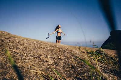 Young woman standing in field against clear sky