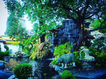 Statue by trees against water