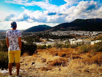 Rear view of man standing by mountain against sky