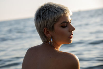 Side view of young woman looking away at beach