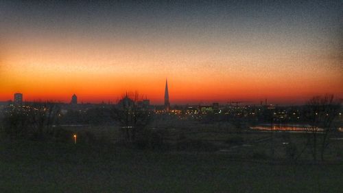 Scenic view of city against dramatic sky during sunset