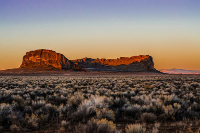 Rock formations in desert against sky during sunset