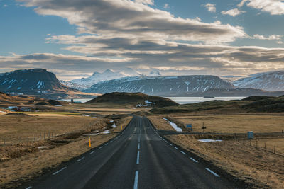 Road by mountains against sky