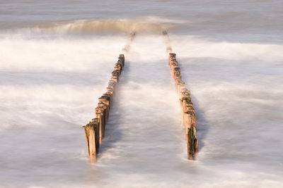 High angle view of wooden posts in sea against sky