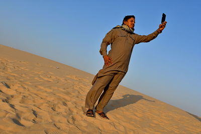 Man taking selfie while standing on sand at beach