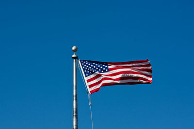 Low angle view of flags against clear blue sky