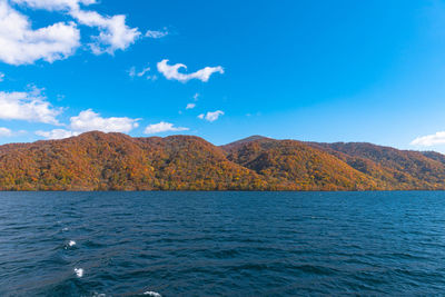 Scenic view of sea and mountains against blue sky