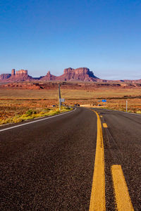 Road by desert against clear blue sky