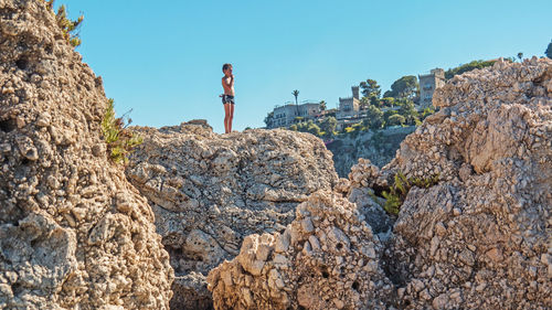 Low angle view of woman standing on cliff against sky