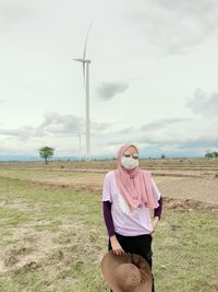 Woman wearing hijab and mask while standing at farm