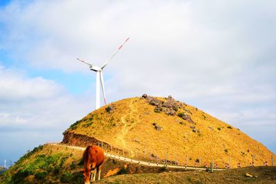 Low angle view of wind turbines on land against sky