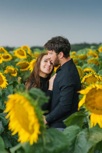 A happy couple in love are walking in summer among sunflowers