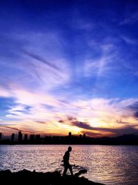 Silhouette man on beach against sky during sunset