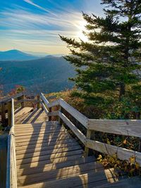 Shadow of railing on bridge against sky
