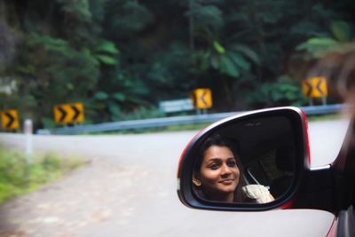 Young woman reflecting on car side-view mirror