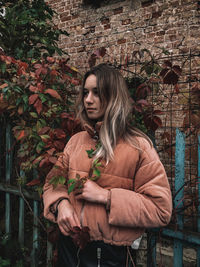 Beautiful young woman standing against brick wall