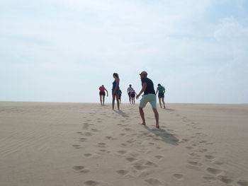 People at sandy beach against sky