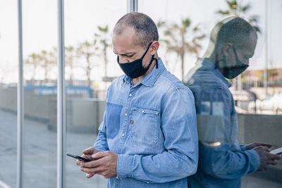 Middle-aged latino man with mask consults the smartphone