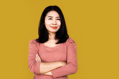 Portrait of a smiling young woman against yellow background