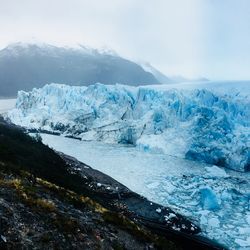 Scenic view of icebergs and mountains against sky