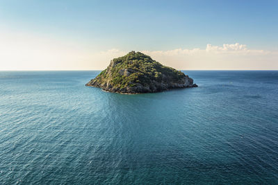 Rock formation in sea against blue sky