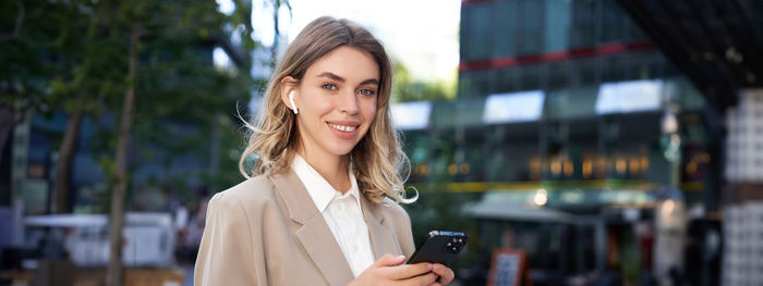 Portrait of young woman standing in city