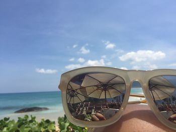 Close-up of sunglasses on knee with reflection against sky