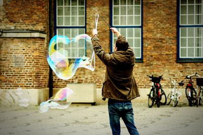 Rear view of man with large bubble on street