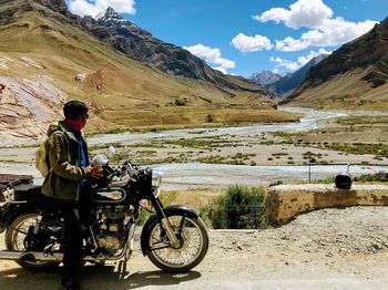 Man riding bicycle on mountain against sky