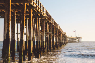 Pier on beach against clear sky